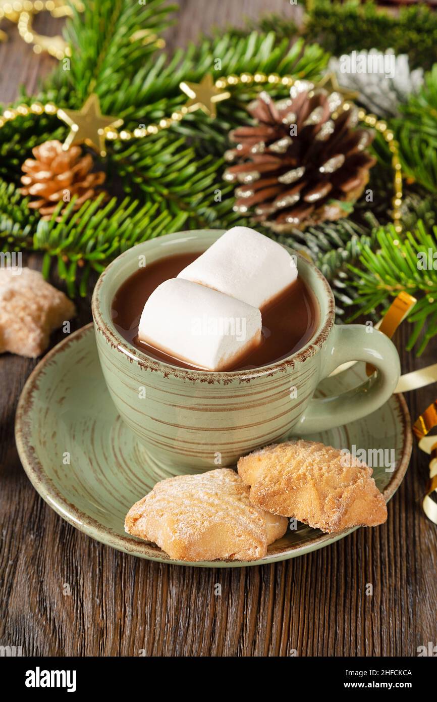 Heiße Schokolade, traditionelles Weihnachtskakaogetränk, süße hausgemachte Kekse und Dekorationen auf braunem Holzhintergrund. Stockfoto