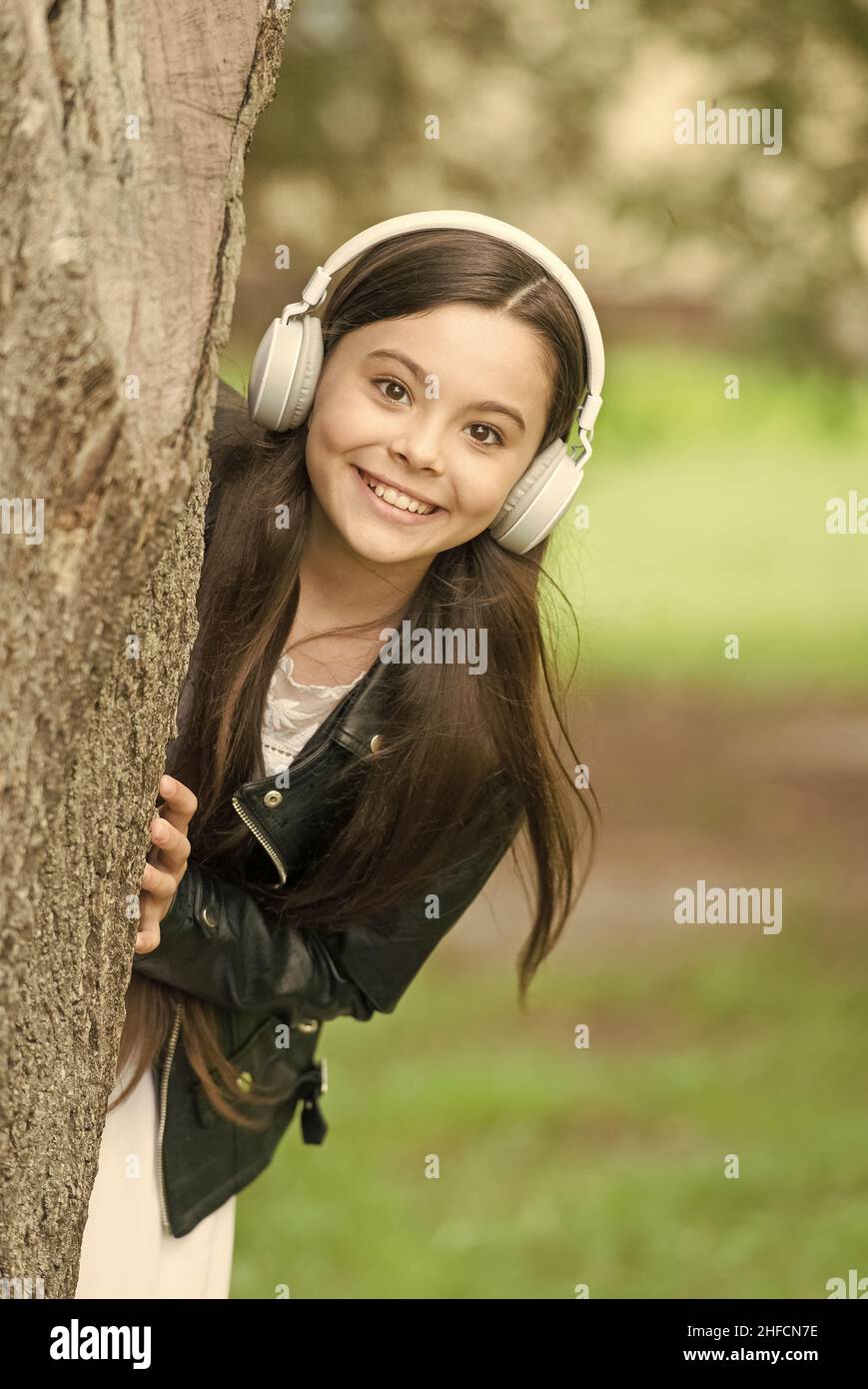 Babytechnik. Fröhliches Kind trägt Kopfhörer im Freien. Kleines Mädchen hören Musik in Kopfhörern. Gehörschutz. Kopfhörer mit Geräuschminimierung. Neu Stockfoto