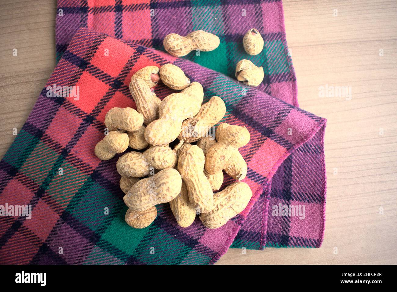 Erdnüsse auf einer bunten Serviette auf einem beigen Tisch. Stockfoto