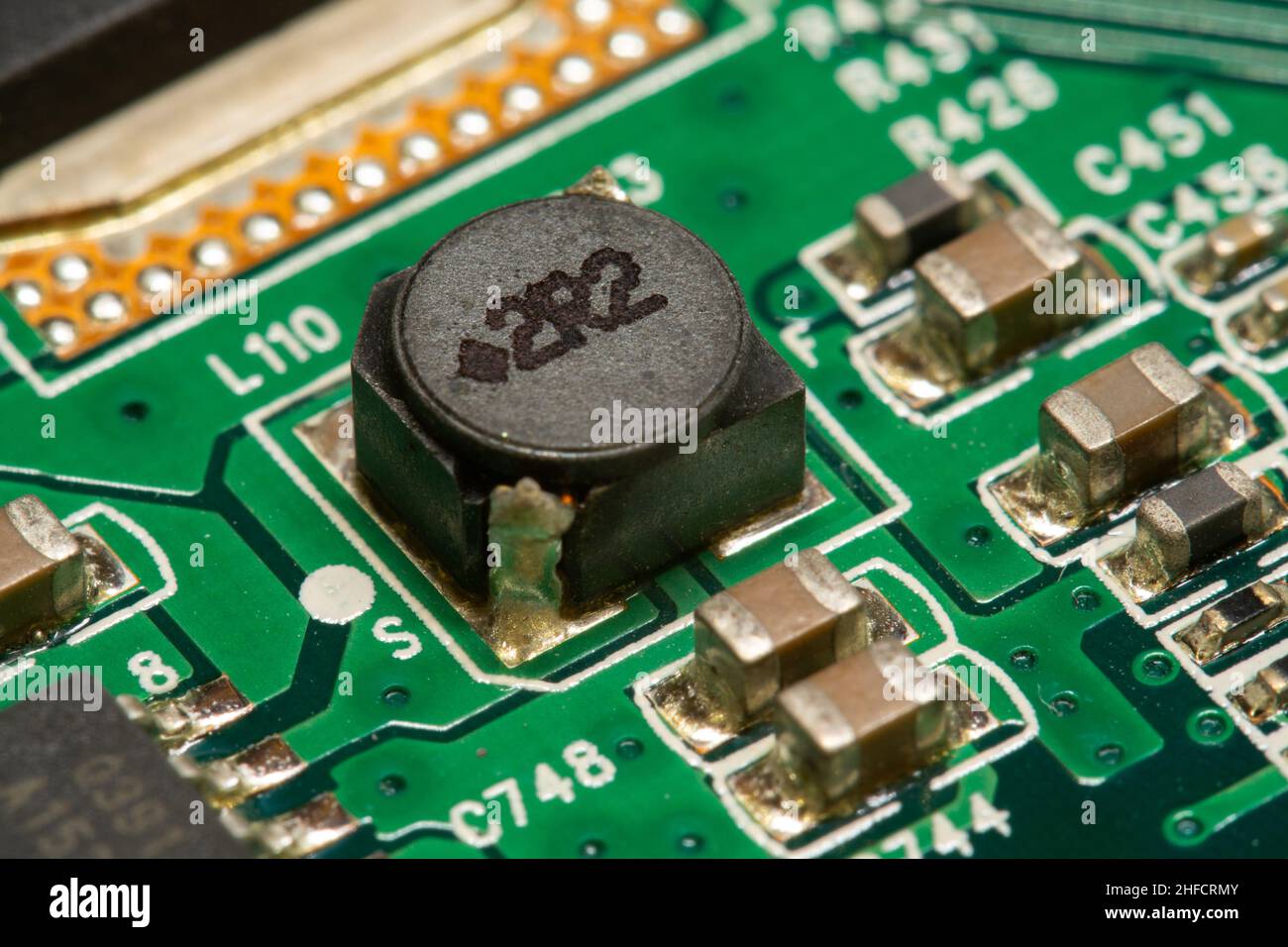 SMD-Induktivität und andere elektronische Bauteile, die auf einer grünen Leiterplatte (PCB) gelötet sind. Stockfoto