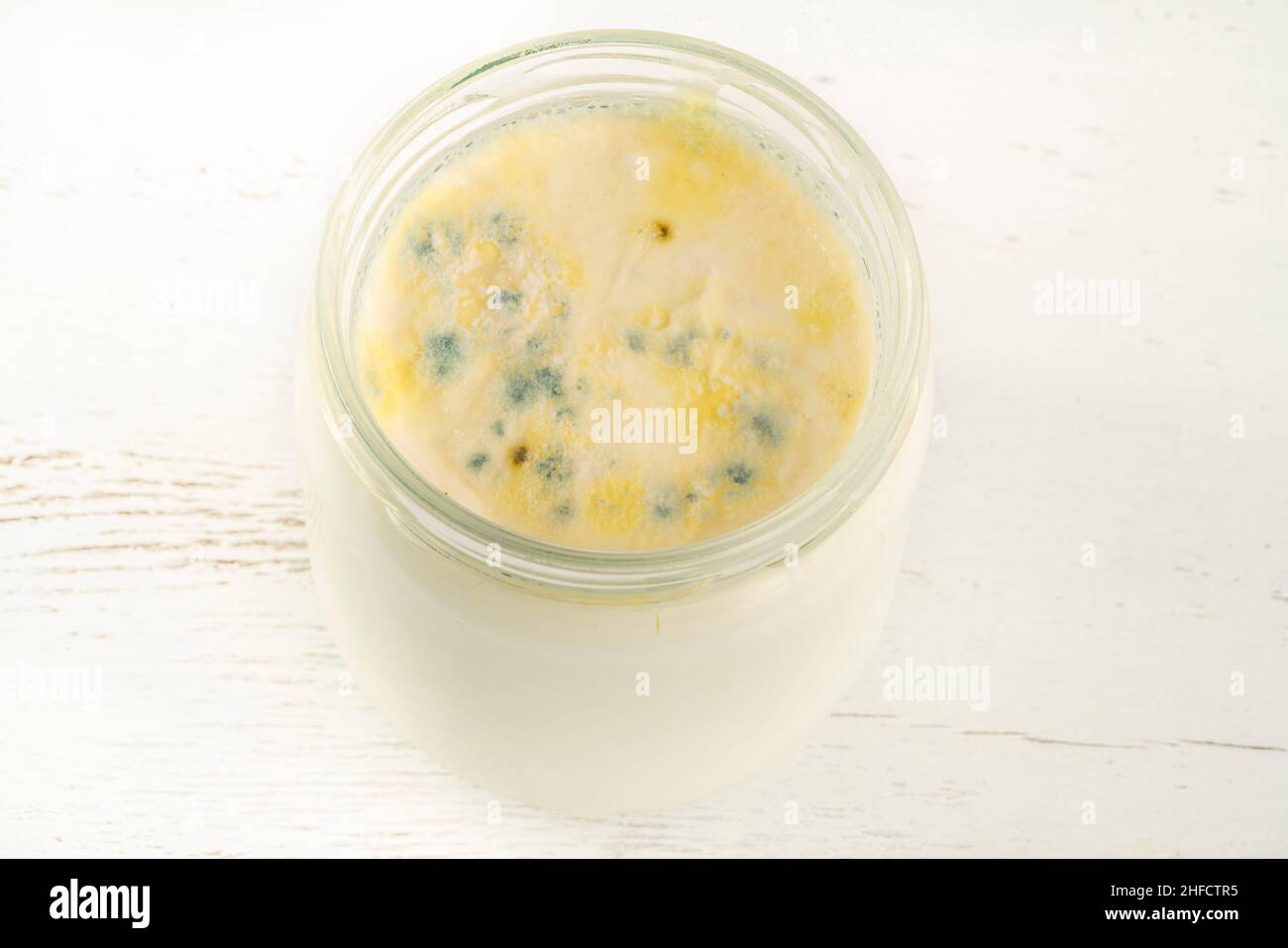 Schimmeliger Joghurt, Schimmelbildung auf Joghurt oder Milchproduktlebensmitteloberfläche überschritten Verfallsdatum. Verfaulter Joghurt oder Milchhintergrund Stockfoto