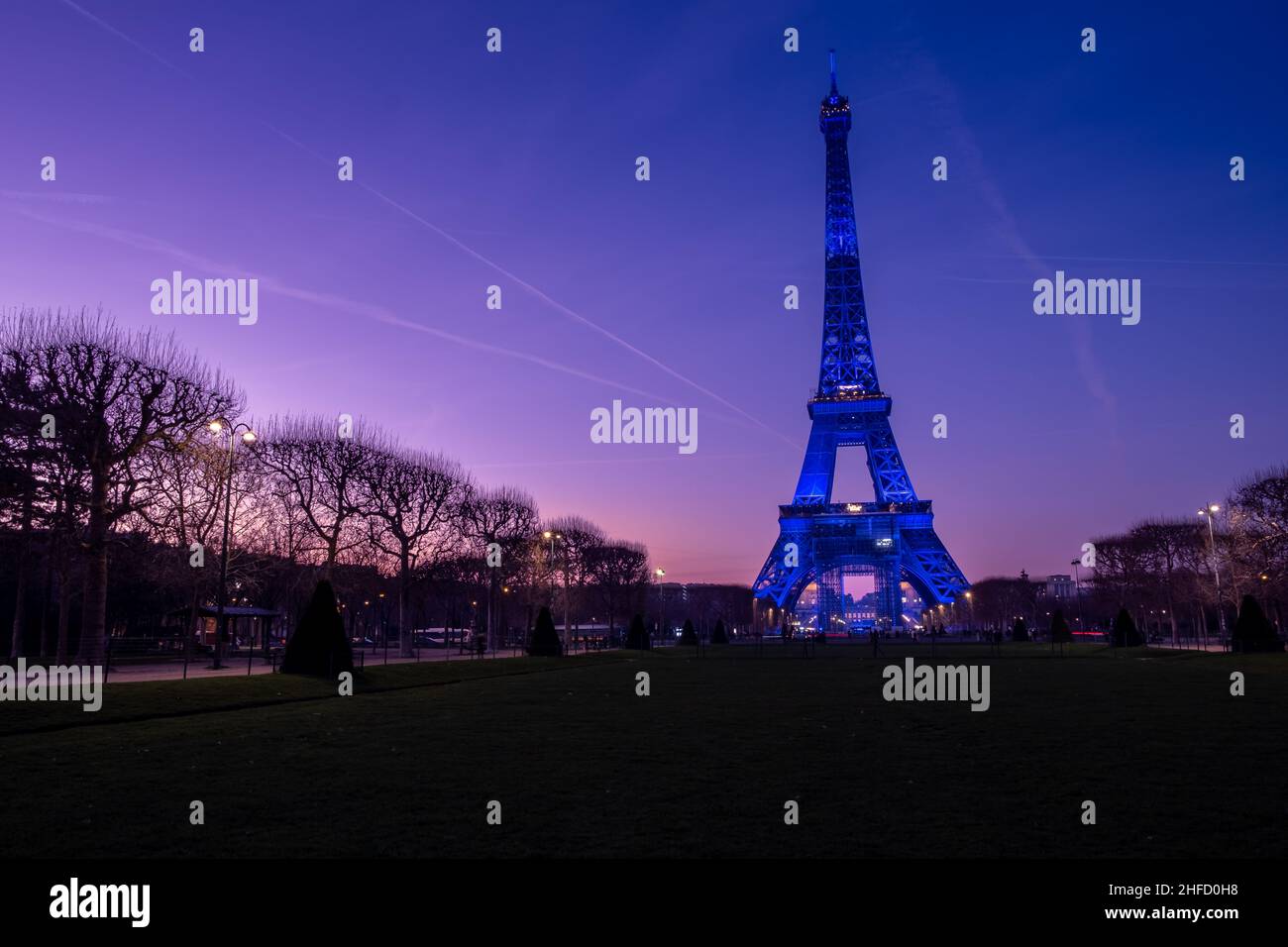 Eiffelturm in blauer Beleuchtung bei Sonnenuntergang mit buntem Himmel Stockfoto