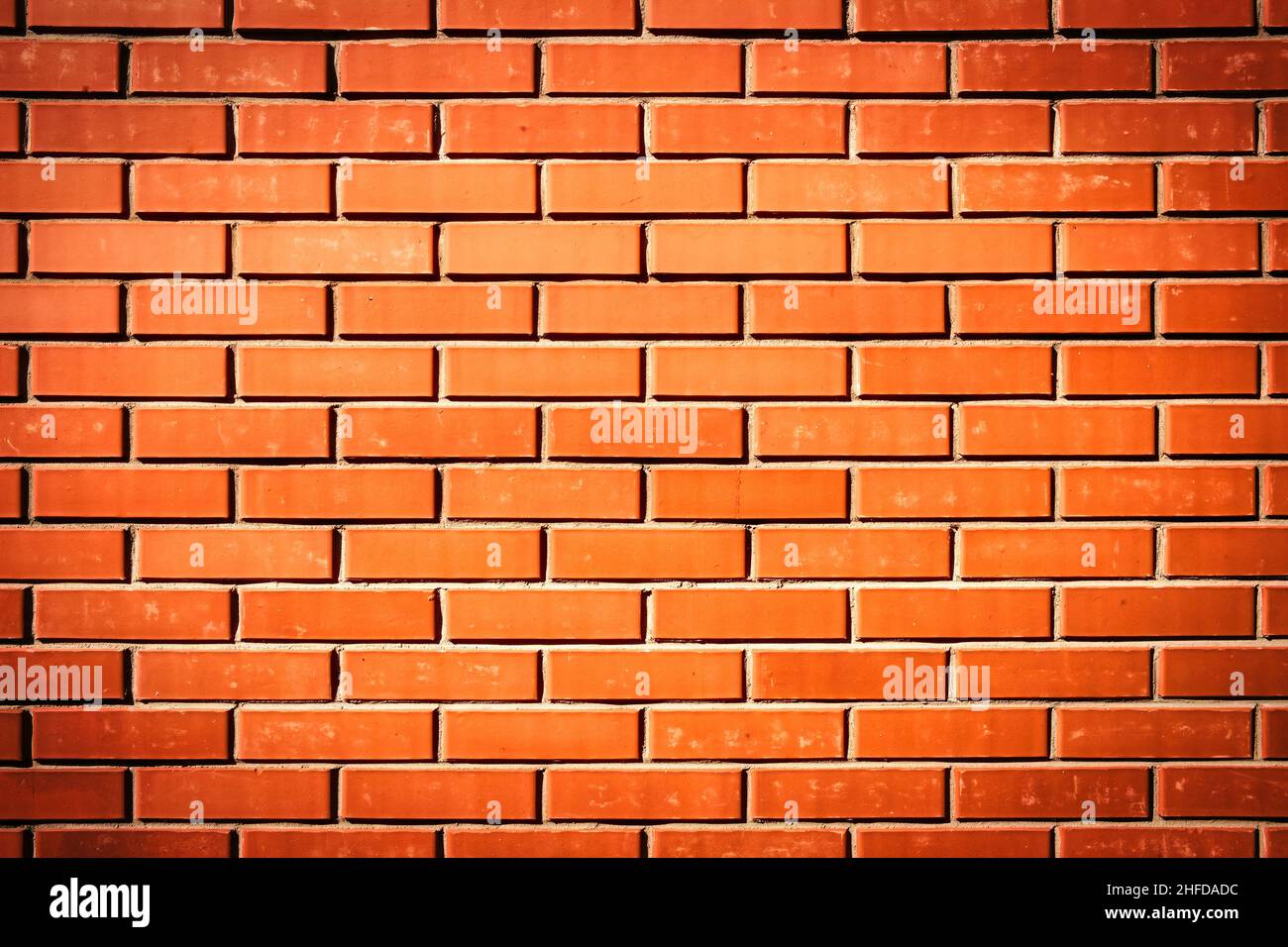 Rote Backsteinmauer. Hintergrund eines neuen Backsteinhauses mit starkem Vignetteneffekt. Stockfoto
