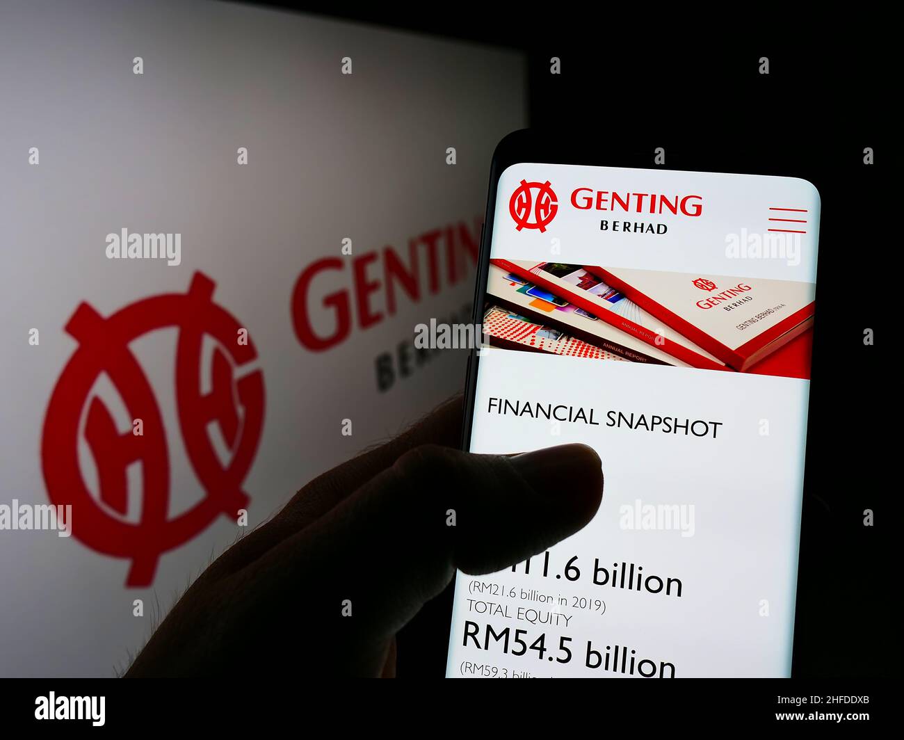 Person, die Mobiltelefon mit der Webseite des malaysischen Konglomerats Genting Group auf dem Bildschirm vor dem Logo hält. Konzentrieren Sie sich auf die Mitte des Telefondisplays. Stockfoto