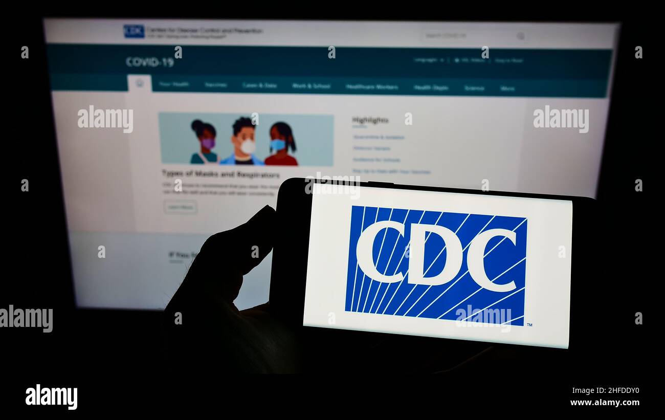 Person, die das Smartphone mit dem Logo der Centers for Disease Control and Prevention (CDC) auf dem Bildschirm vor der Website hält. Konzentrieren Sie sich auf die Telefonanzeige. Stockfoto