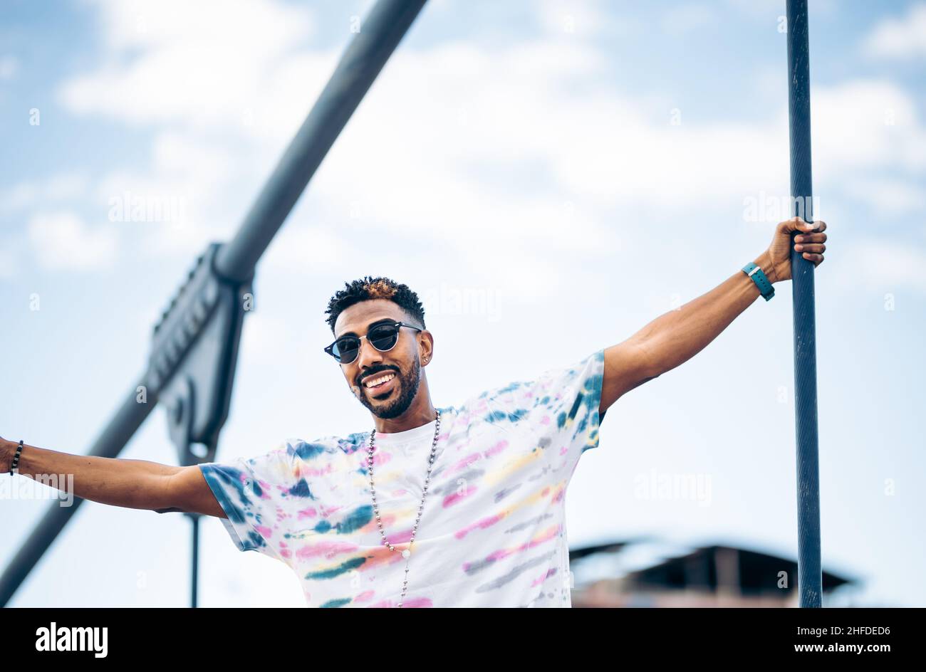 Lächelnder schwarzer Mann in Sonnenbrille erfreut sich mit ausgestreckten Armen und genießt den Moment Stockfoto