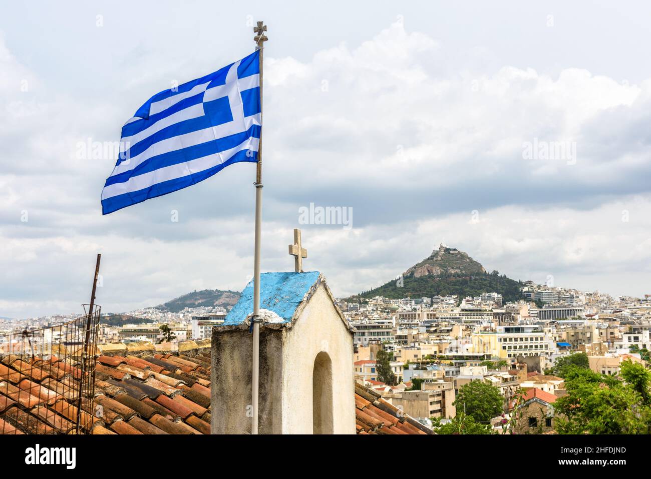 Griechische Flagge in Athen, Ansicht des Lycabettus-Berges vom Plaka-Viertel am Akropolis-Fuß, Griechenland. Es ist Touristenattraktion der Stadt. Skyline von Athen, nat Stockfoto