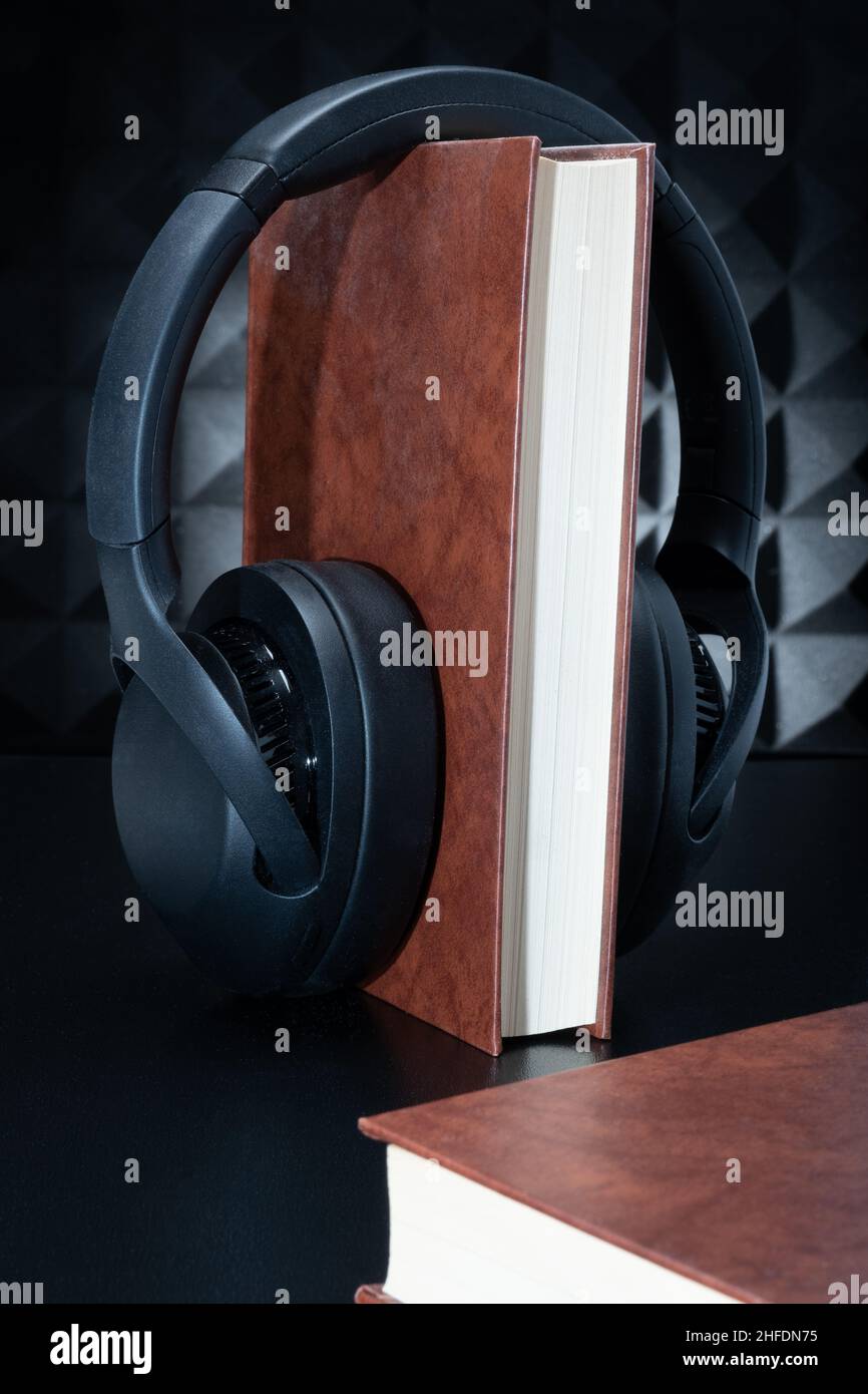 Eine Nahaufnahme eines Hardcover-Buches mit Kopfhörern. Konzept eines Hörbuchs. Stockfoto