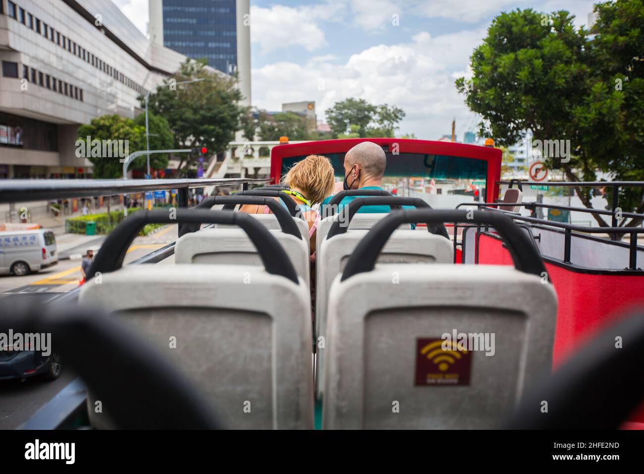 Touristenpaar in einem Bus mit offenem Oberdeck, der durch die zentrale Gegend Singapurs fährt, um Sehenswürdigkeiten zu besichtigen. Stockfoto