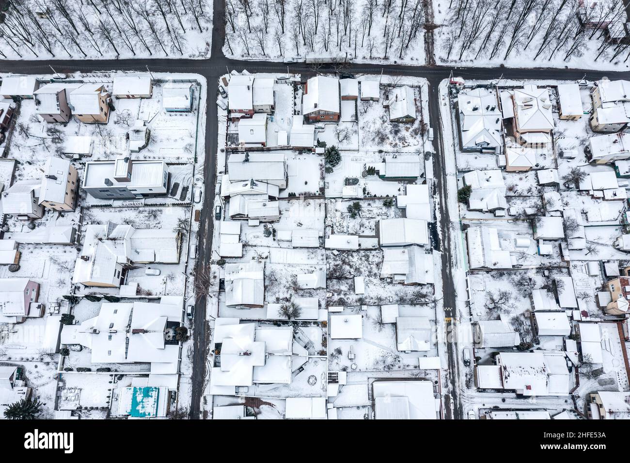 Luftaufnahme von verschneiten Häusern und Straßen in einem Vorort-Wohngebiet. Drohnenfoto. Stockfoto