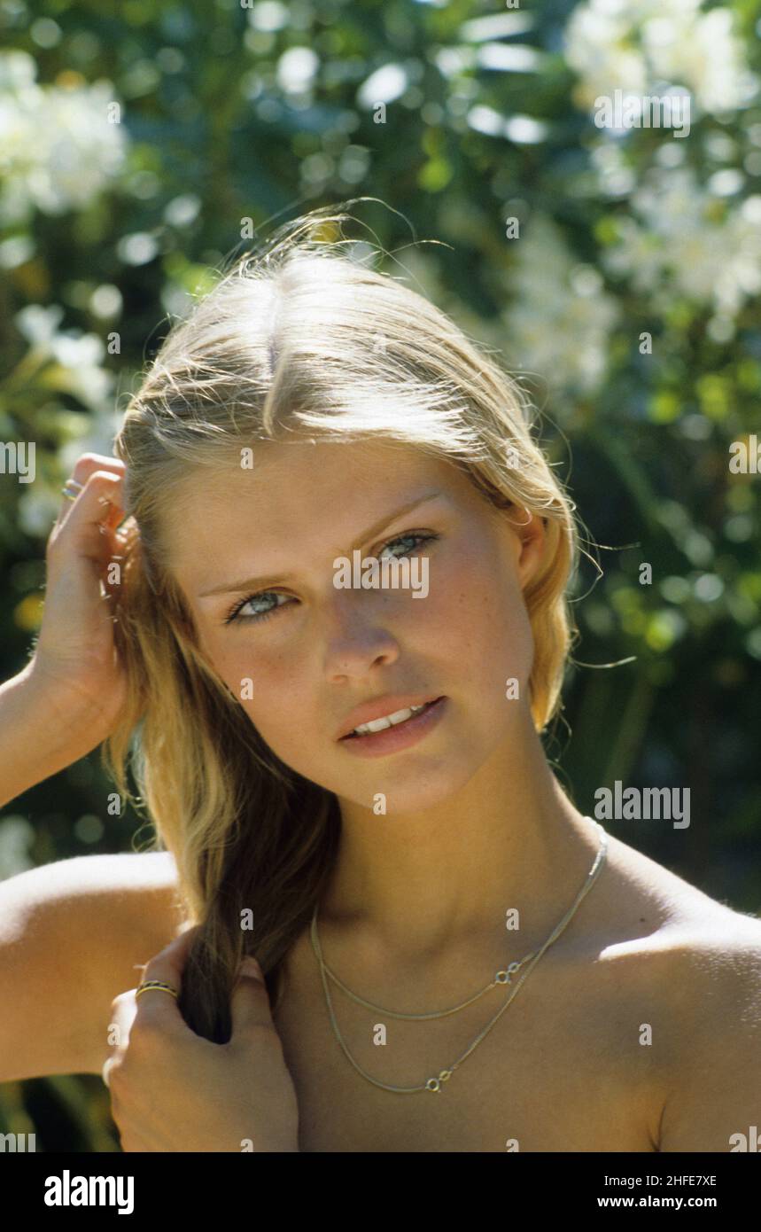 Lächelnd und glücklich blonde Haare junge Frau Nahaufnahme Porträt Profil suchen Kamera grün Laub Hintergrund natürliches Licht Stockfoto
