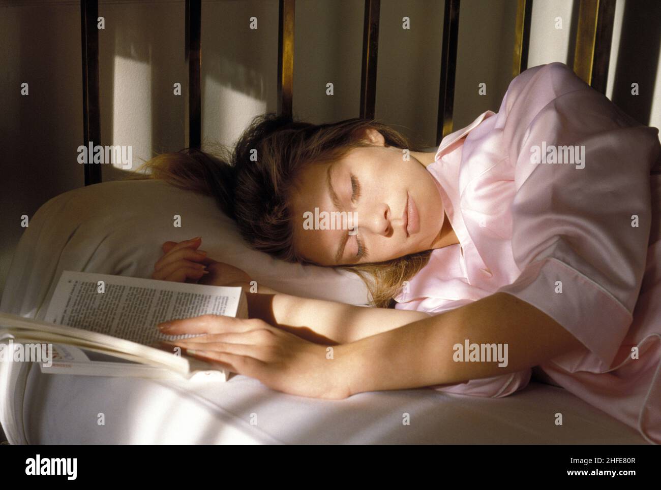 Ziemlich blonde Haare Schönheit schlafen Gesicht im Bett Portrait Profil ansehen Kamera mit weichem sonnigen Strahl sehr müde Buch öffnen Stockfoto