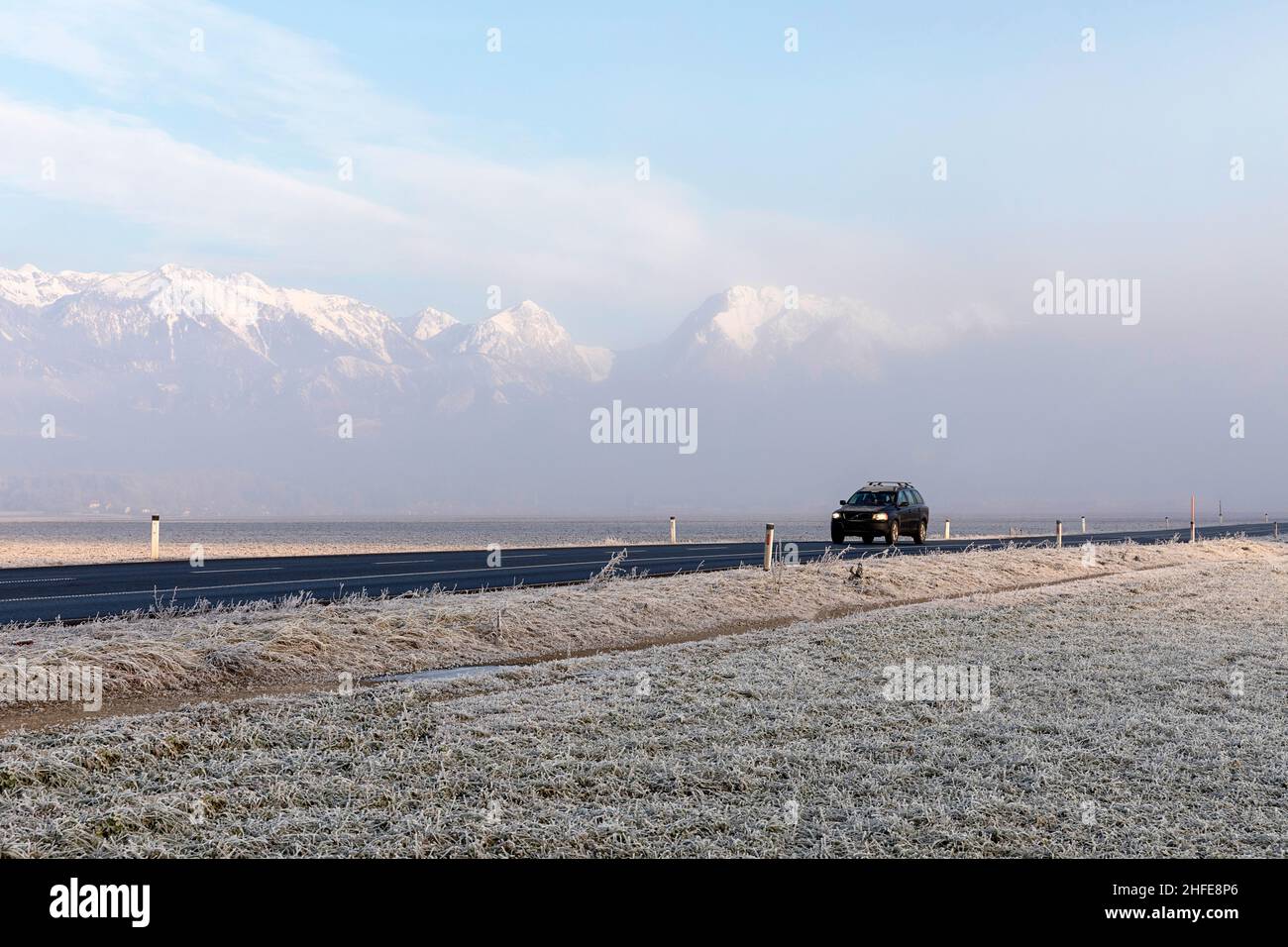 Autofahren auf der Straße mit schneebedeckten Gipfeln der Kamnik-Savinja-Alpen, die im morgendlichen Frost aus Nebel ihren Höhepunkt erreichen, Menges, Slowenien Stockfoto