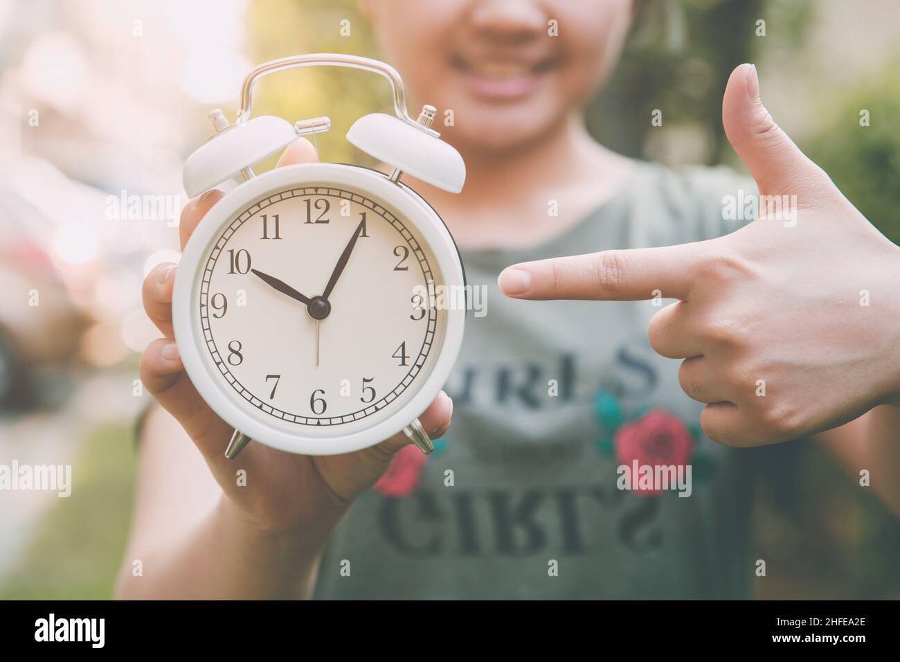 Nahaufnahme glücklich teen Mädchen Hand zeigt auf vintage Glocke Uhr für erinnern oder es ist Zeit Konzept Stockfoto