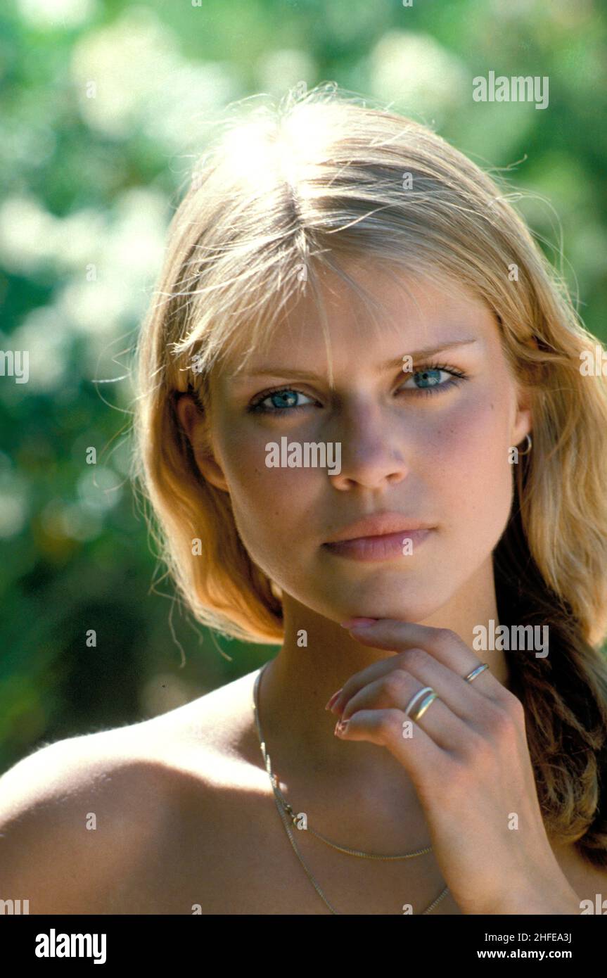 Blonde Haare ausdrucksstark lächelnd glücklich junge Frau Porträt suchen Frontkamera unterhellgrün natürlichen Laub Hintergrund Stockfoto