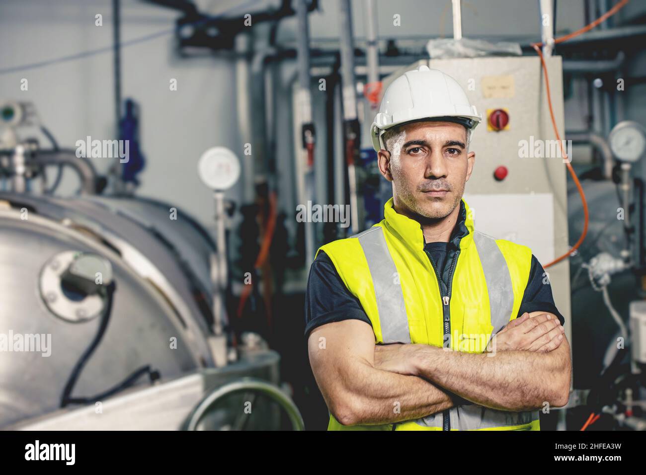 Portrait intelligenter europäischer Ingenieur, der lächelnd in einer schweren Industriefabrik nach der Zukunft sucht. Stockfoto