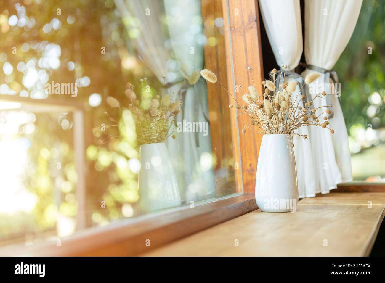 Holztischtisch an der Fensterseite mit getrockneten Blumentöpfen im Café Stockfoto