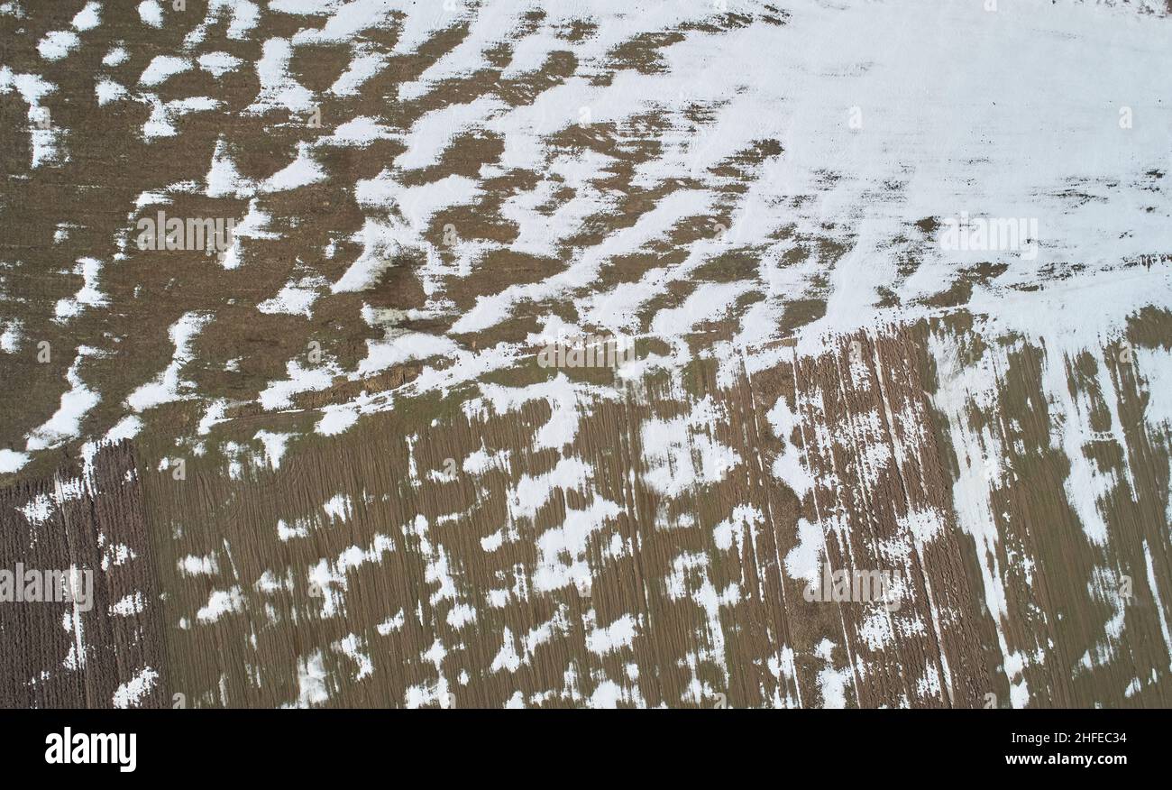 Abstarkt braunes Bodenmuster über Drohne Draufsicht. Schneelinien in der Erde Stockfoto