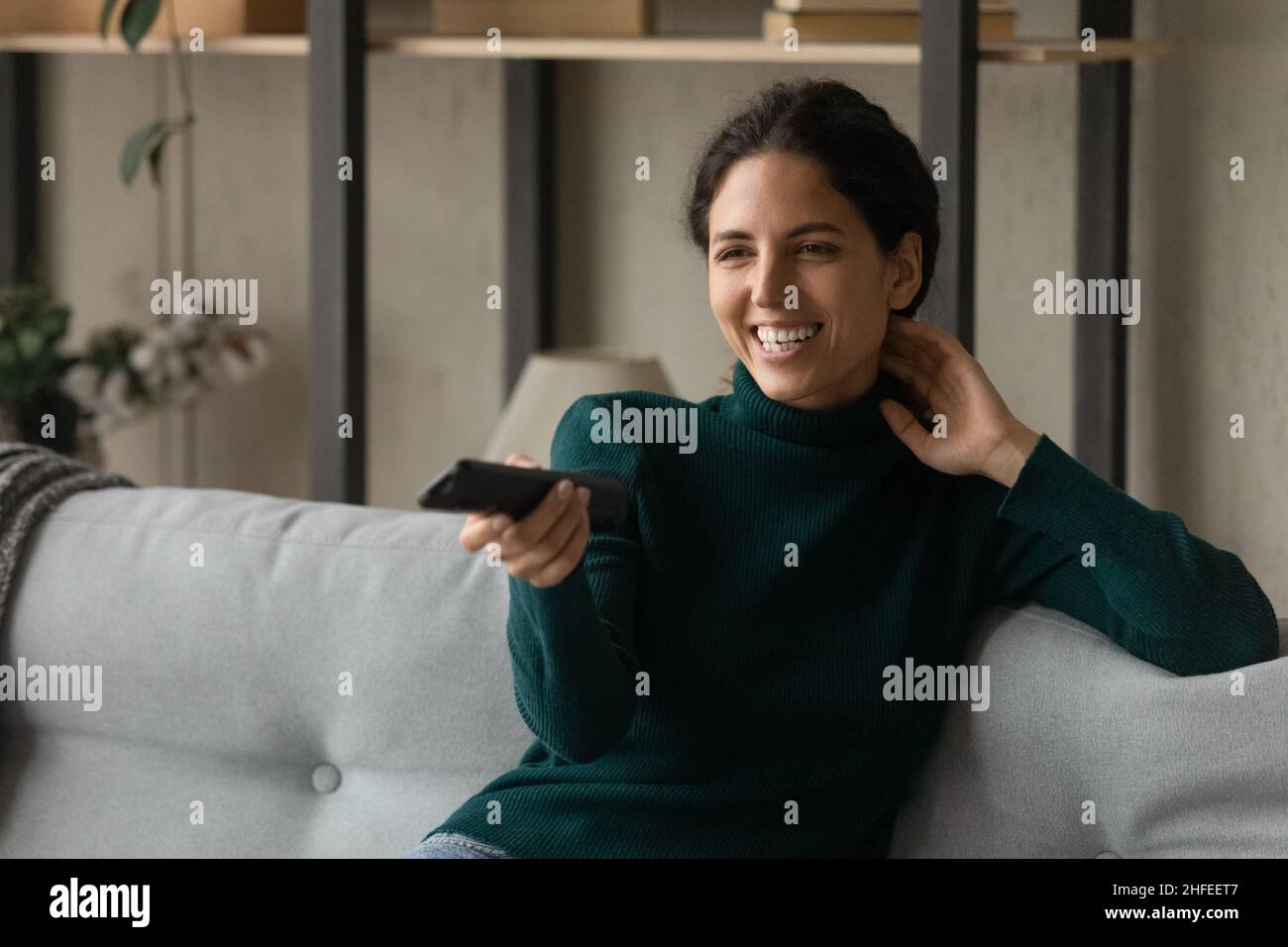Glückliche junge Frau, die zu Hause Smart-TV-Shows sieht. Stockfoto