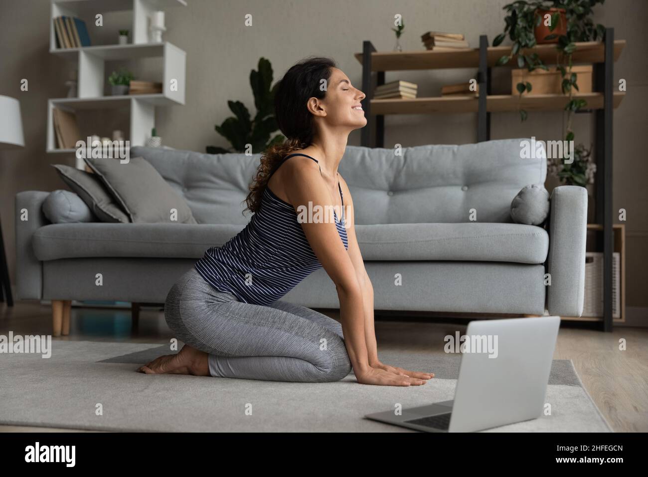 Lächelnde sportliche junge Frau macht Yoga-Atemübungen. Stockfoto