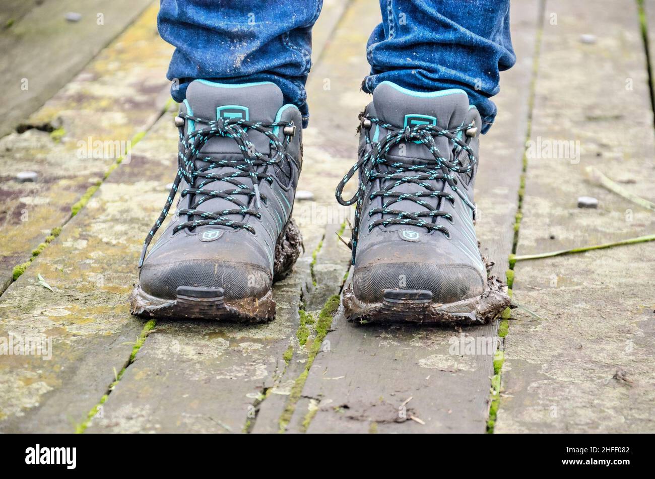 Oudewater, Niederlande. 6. Dezember 2020: Schlammige Wanderschuhe, die von einem Wanderer auf einer verwitterten Holzbrücke als Teil des Tiendweges getragen werden Stockfoto