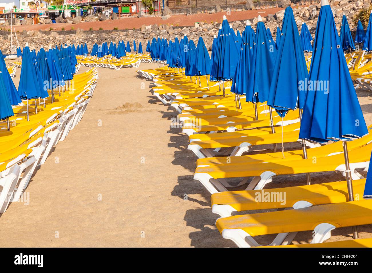 Sonnenschirme und leere Liegen am Strand bei Morgenlicht Stockfoto