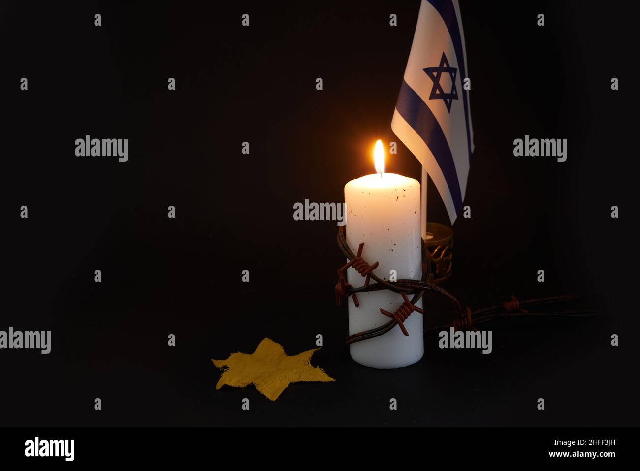 Holocaust-Gedächtnistag. ARBED Draht und brennende Kerze auf schwarzem Hintergrund Stockfoto