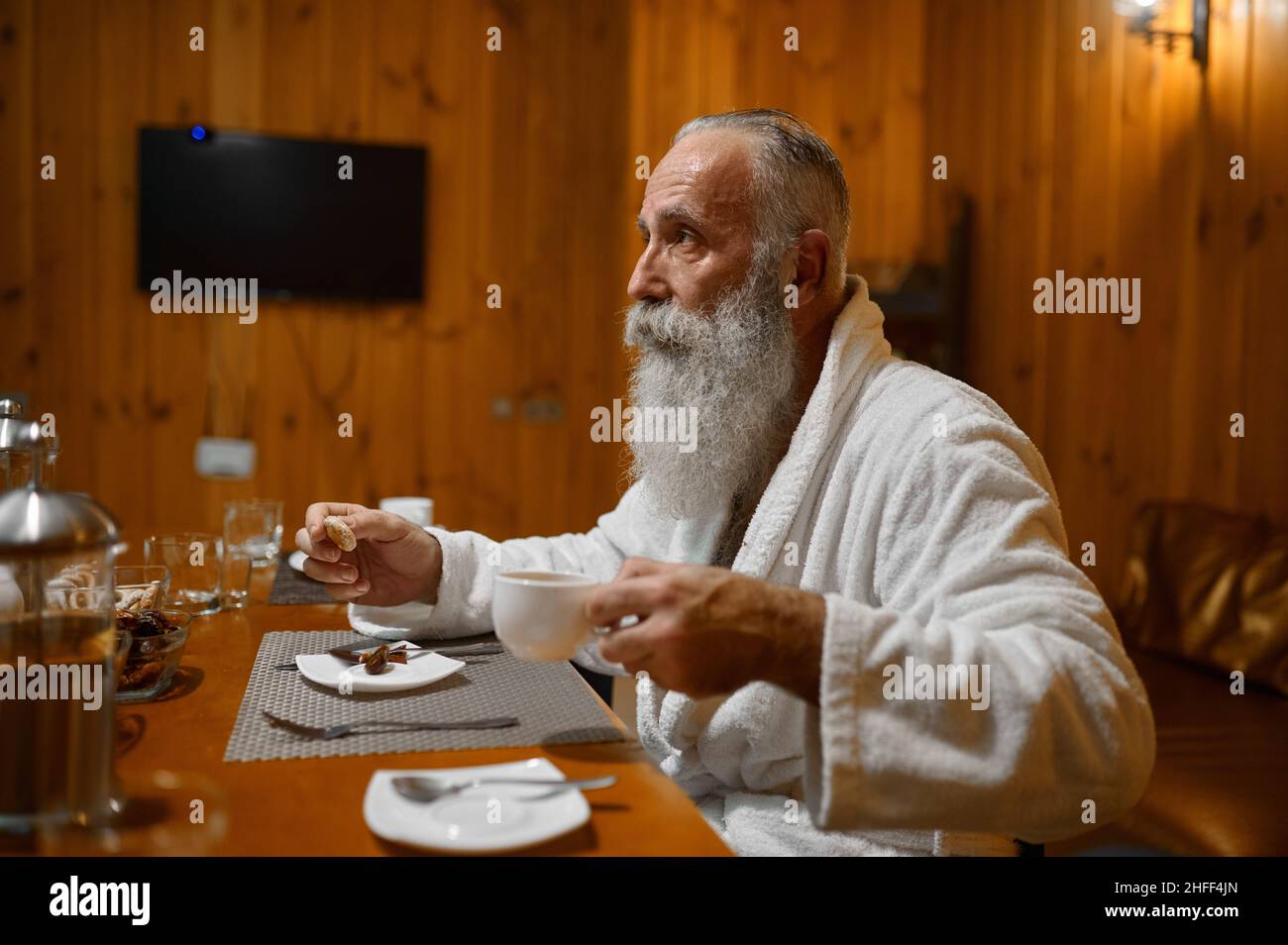 Seniorchef trinkt Tee, Erholung in der Sauna Stockfoto