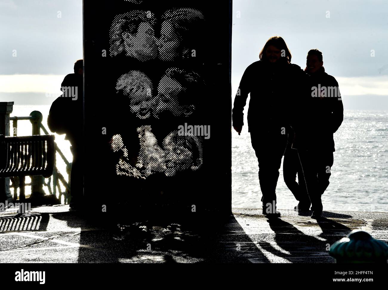 Brighton UK 16th January 2022 - Spaziergänger kommen an der Kiss Wall Skulptur an der Küste von Brighton vorbei, da für Großbritannien in den nächsten Tagen ein eher sessoreres Wetter prognostiziert wird: Credit Simon Dack / Alamy Live News Stockfoto