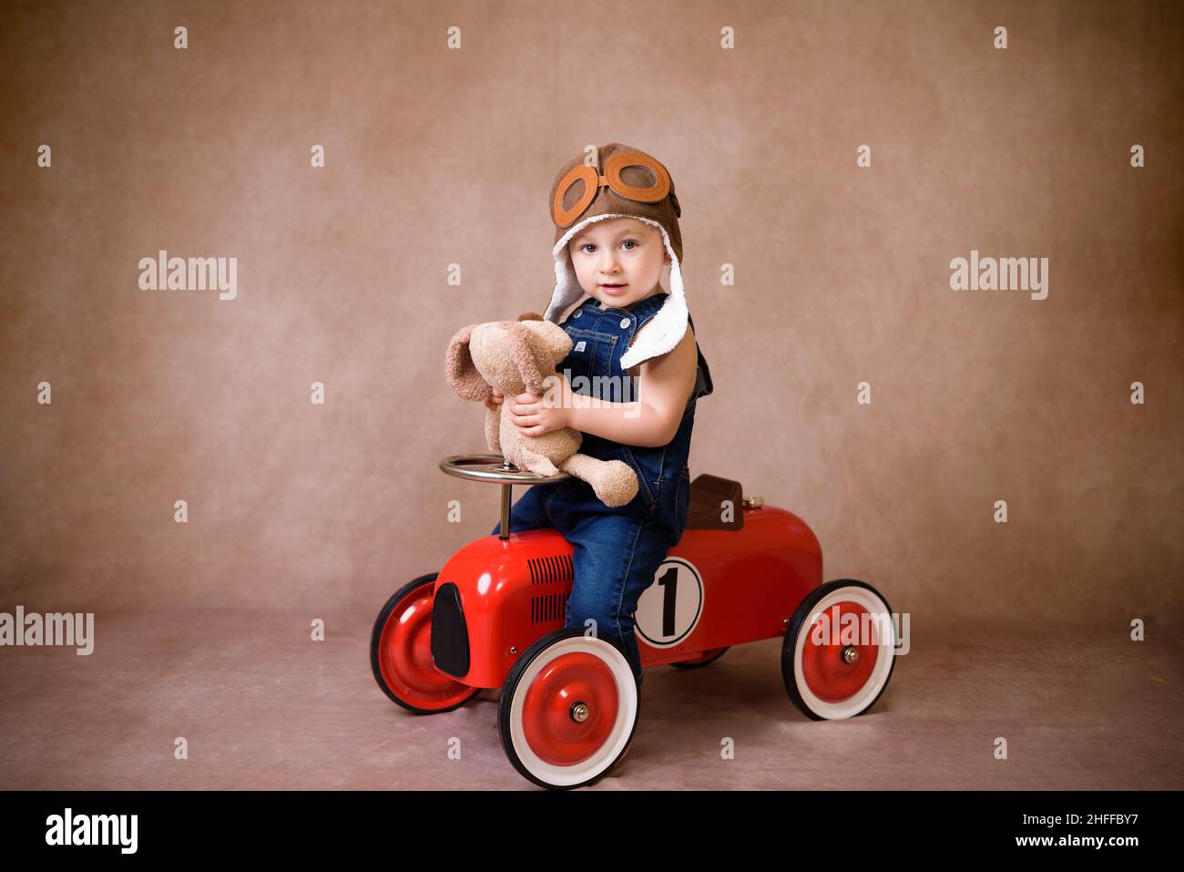 Kind fährt im roten Auto. Kind mit Weihnachtstasche. Weihnachtsfeiertagskonzept Stockfoto