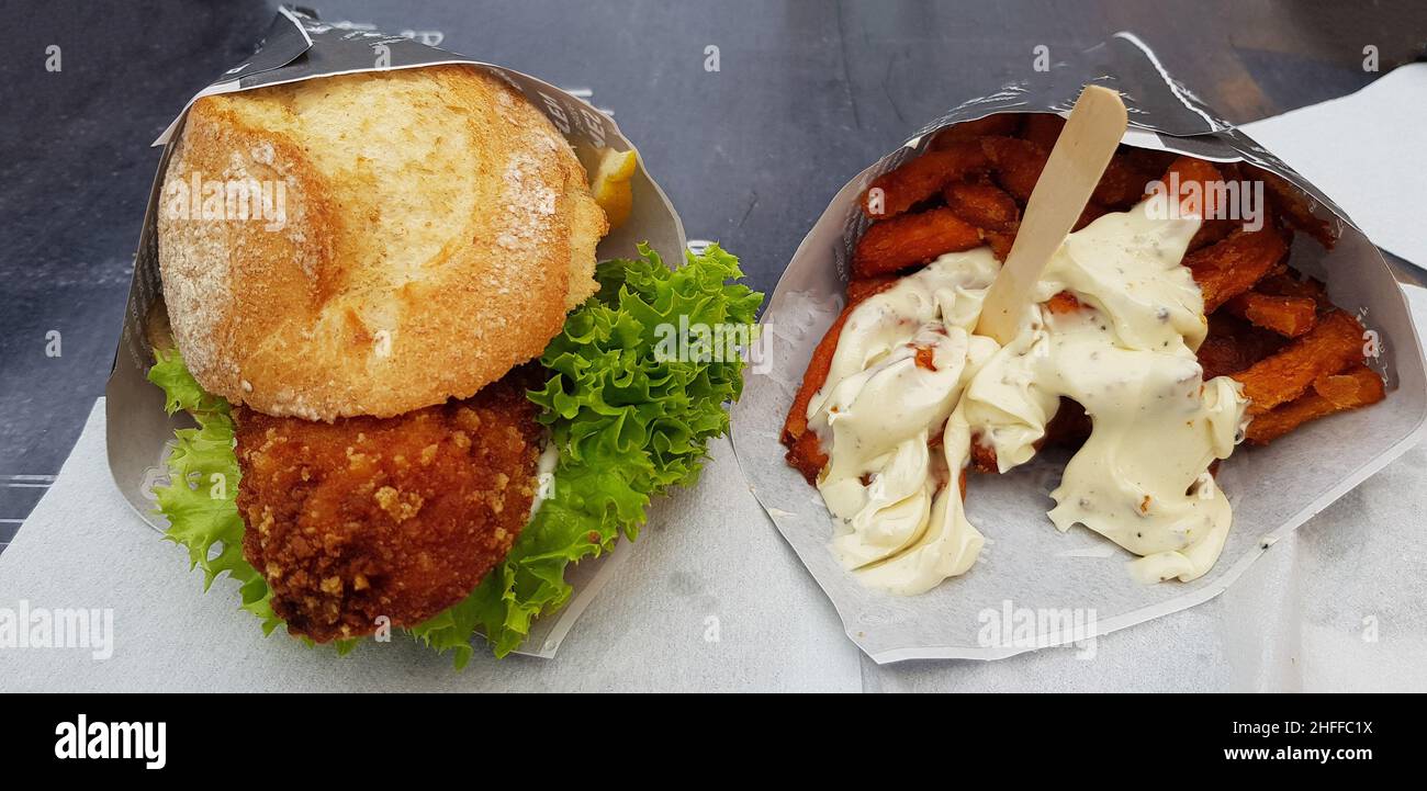 Gebackene Fischbrötchen und Süßkartoffelfrites mit Mayonnaise in einem Papierbeutel aus dem Fast-Food-Restaurant Stockfoto