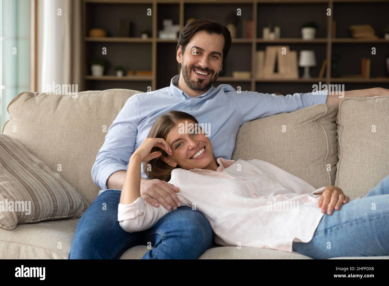 Glückliche Ehegatten, die sich auf dem Sofa entspannen, lächeln und blicken in die Kamera Stockfoto