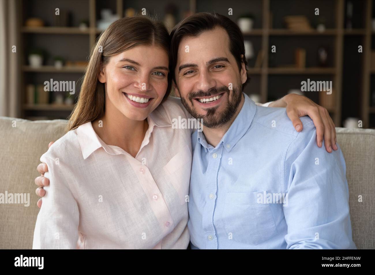 Schönes Paar umarmt sitzen auf dem Sofa Lächeln Blick auf die Kamera Stockfoto