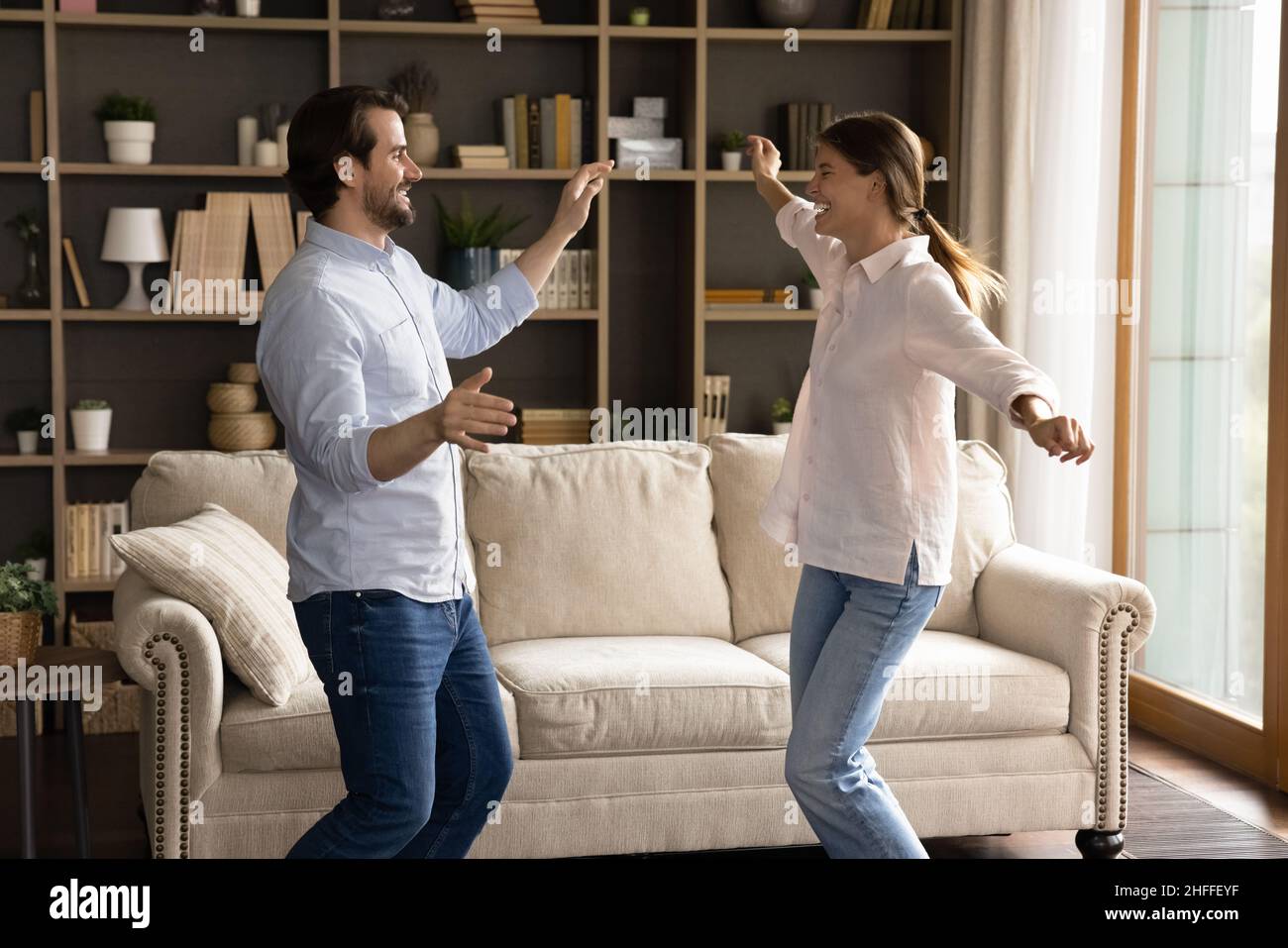 Fröhliches Paar, das im gemütlichen, modischen Wohnzimmer tanzt Stockfoto