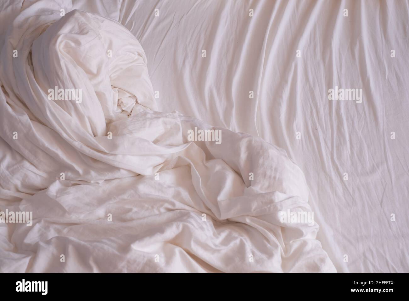 Wunderschöne weiße, glänzende, zerknitterte Stofflaken auf dem Bett. Stockfoto