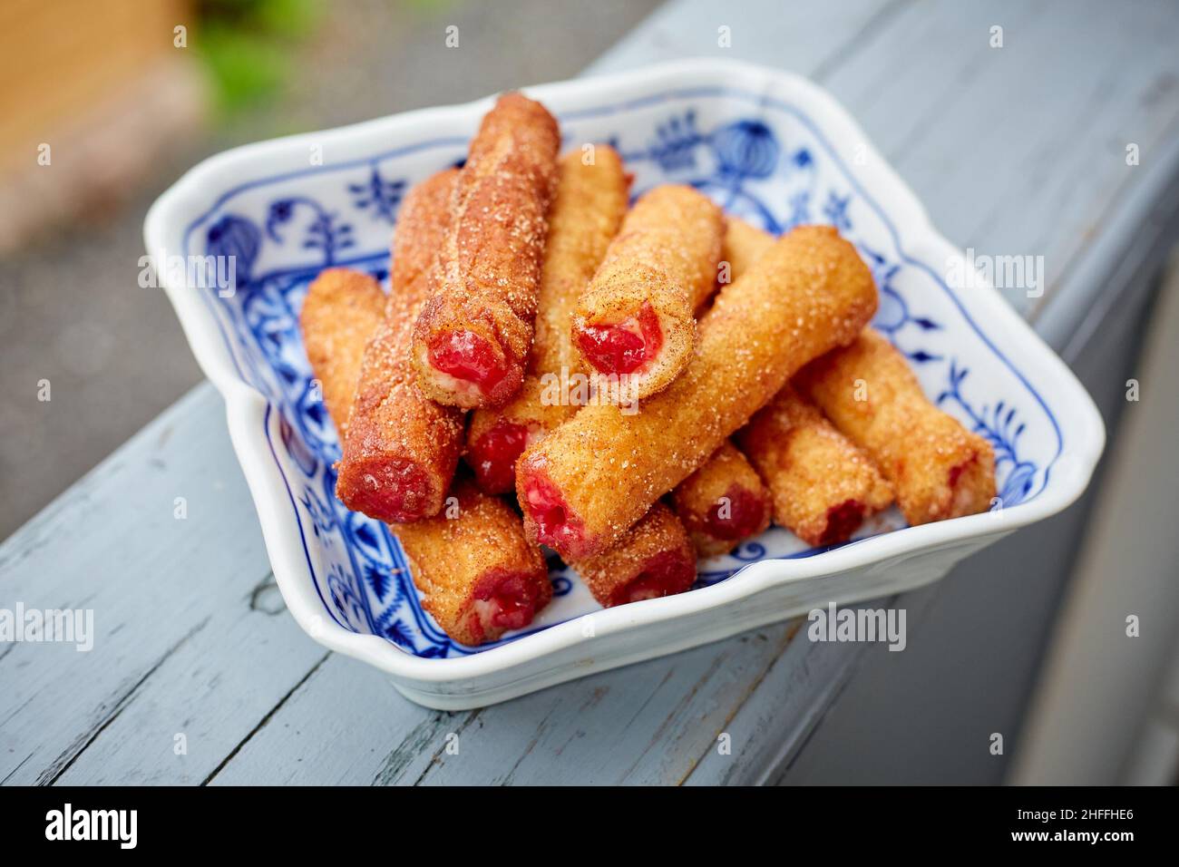 Gefüllte Churros mit frischer Kirschfüllung in Square Bowl auf der Veranda Stockfoto