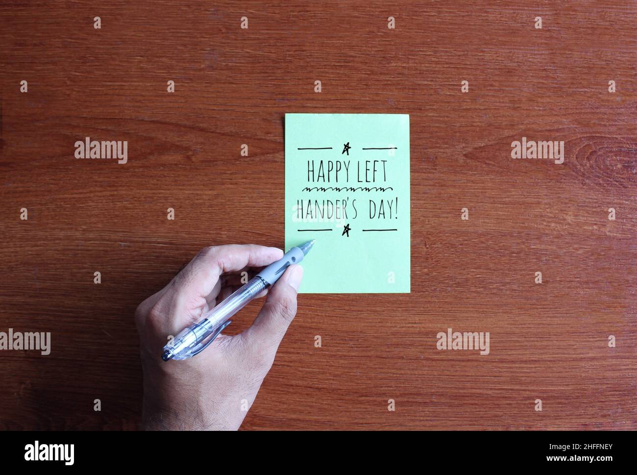 Bild von links oben Text schreiben Happy Left Hander's Day auf grünem Papier auf Holztisch Stockfoto