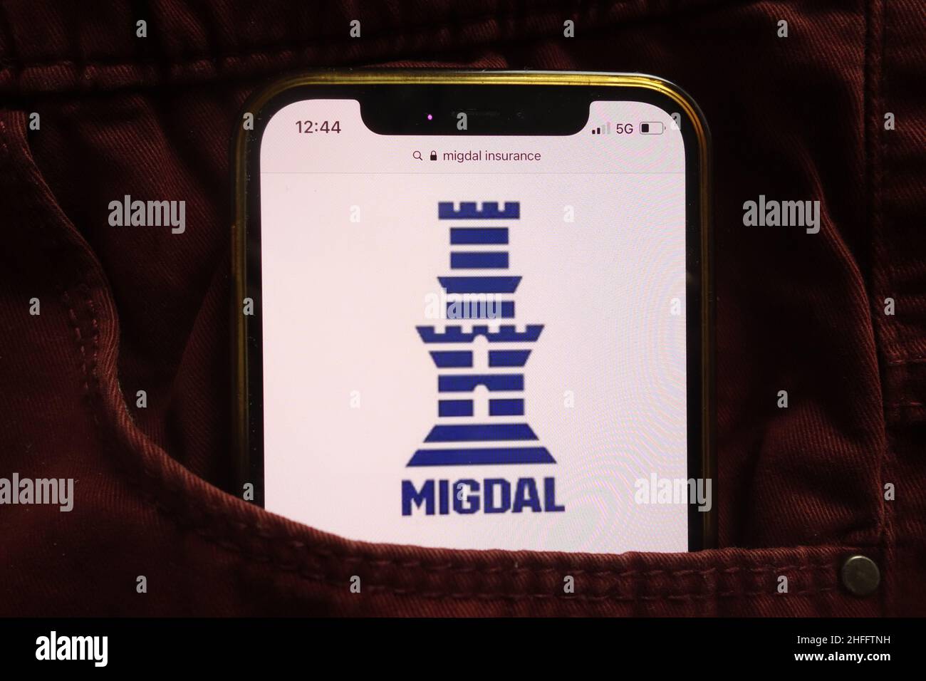 KONSKIE, POLEN - 15. Januar 2022: Das Logo von Migdal Insurance and Financial Holdings Ltd wird auf dem Mobiltelefon in der Jeanstasche versteckt angezeigt Stockfoto