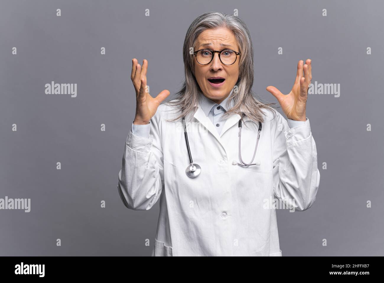 Angst vor einer Coronavirus-Pandemie, einer epidemischen Krankheit. Nahaufnahme eines Porträts einer Frau in Schutzkleid und Brille, die Angst vor der Kamera hat und ihre Hände in der Nähe ihres Kopfes hält Stockfoto