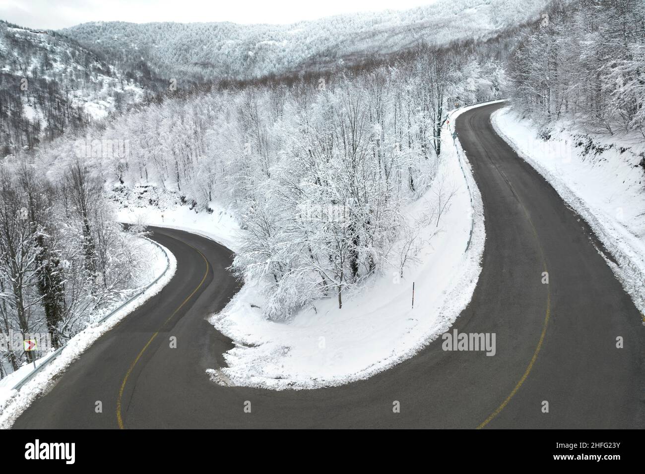 Eine scharfe Kurve auf einer kurvenreichen Straße im Wald. KARTEPE, KOCAELI, TÜRKEI. Schöne Winterlandschaft Luftaufnahme. Stockfoto