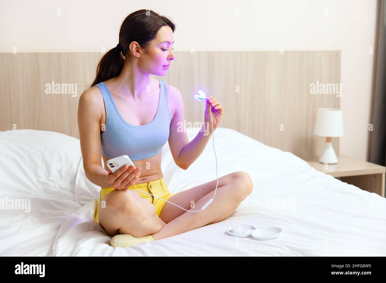 Eine junge Frau verwendet einen Aufhellungskomplex für die Zahnaufhellung zu Hause. USB-UV-Lampe für Zahnaufhellung. Stockfoto