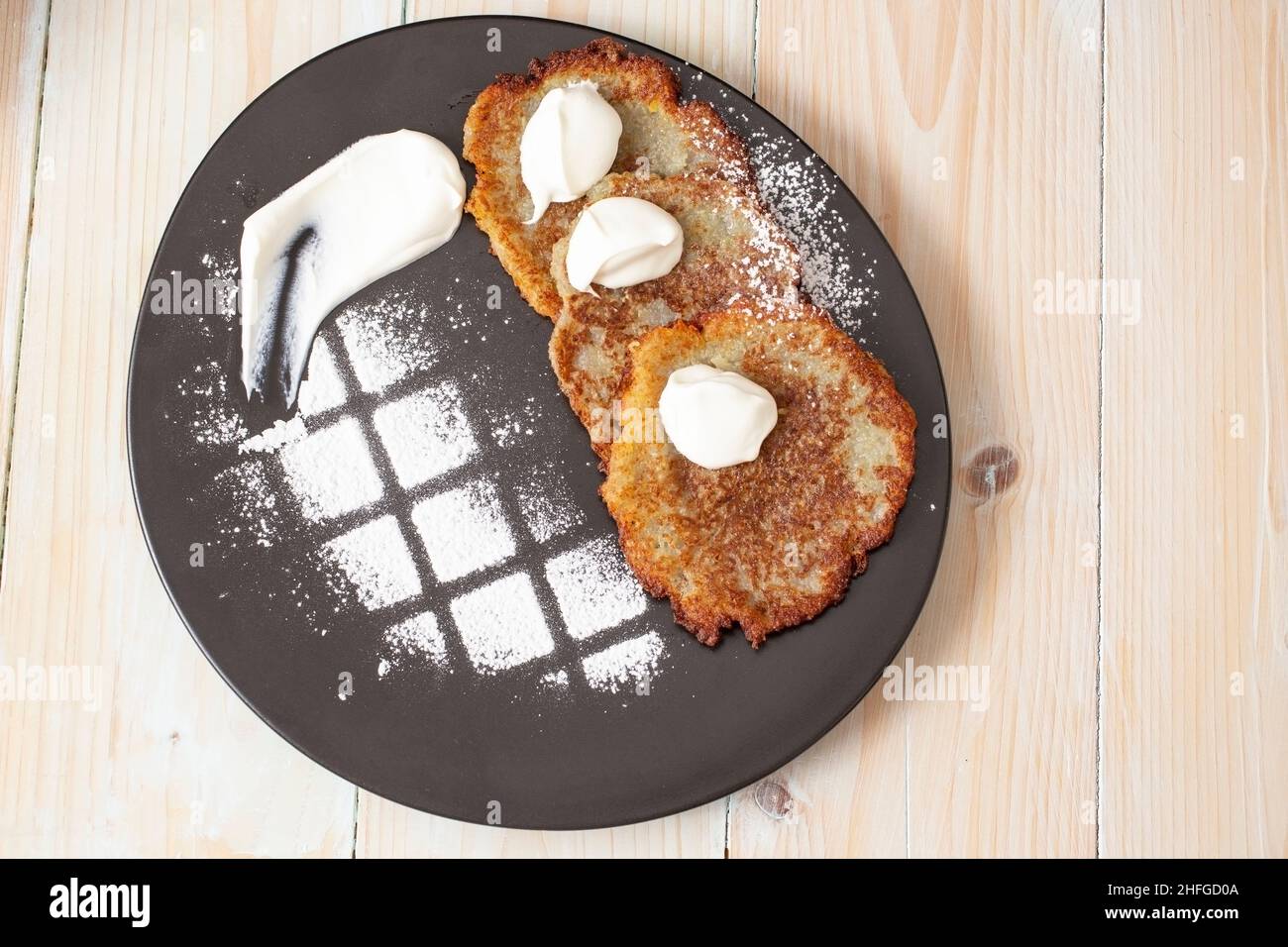 Kartoffelfritter, Draniki, Deruny, Kartoffellatkes, Latkas, irischer Kuchen, Raggmunk, Tocinei oder Boxties, Rösti. Gemüsepfannkuchen auf einem schwarzen Teller Stockfoto