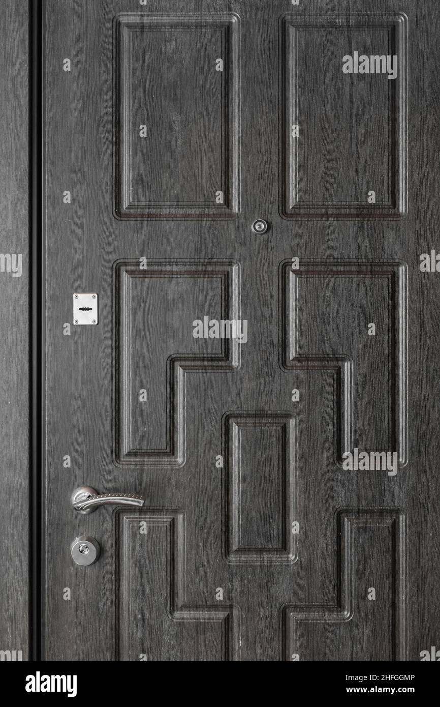 Dunkler Eingang aus Holz, mit Eisengriff, Schlüsselloch und Gußloch. Stockfoto