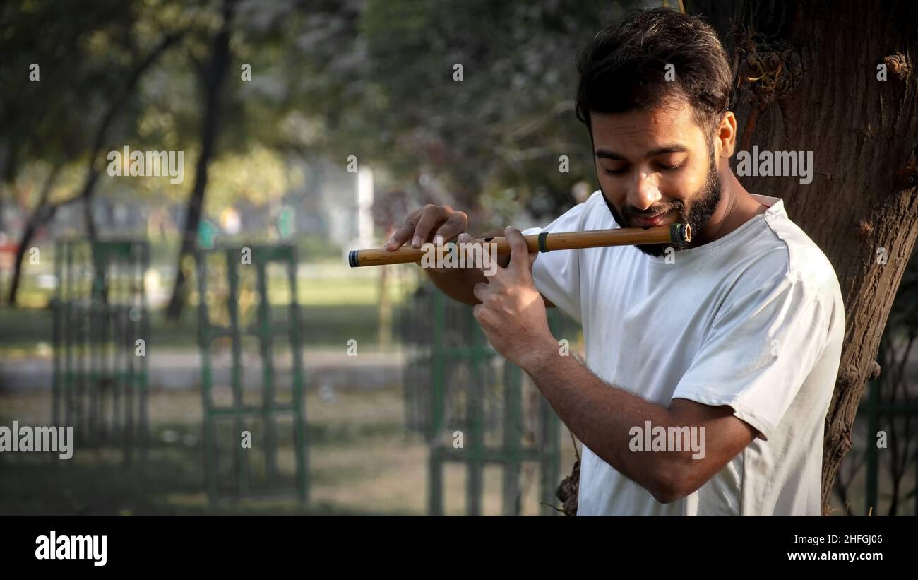 Bansuri-Spieler, der bei Sonnenschein im Park Musik spielt - Indian Flute Player Stockfoto