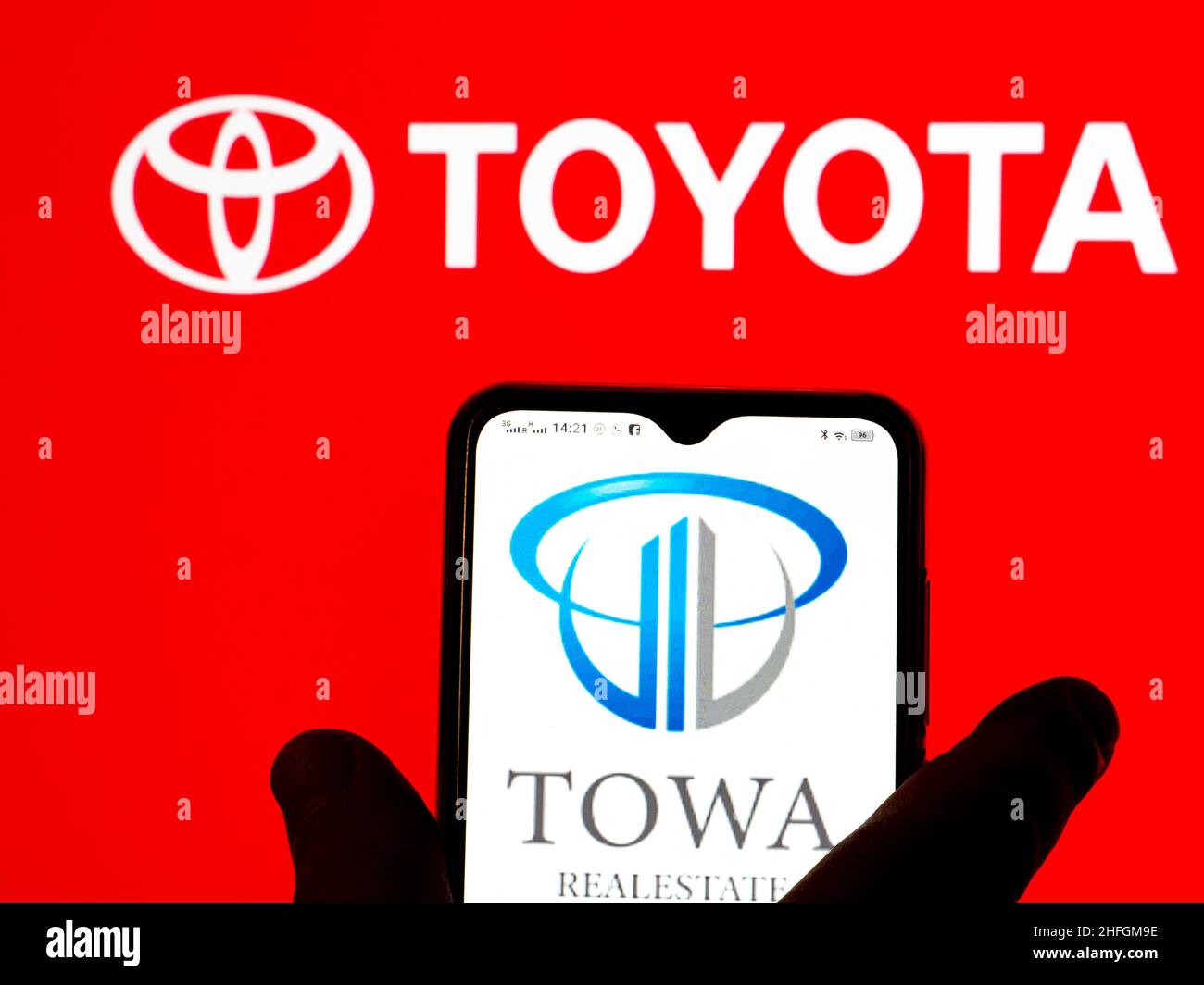 In dieser Abbildung ist das Towa Real Estate Logo auf einem Smartphone-Bildschirm mit dem Toyota-Logo im Hintergrund zu sehen. Stockfoto