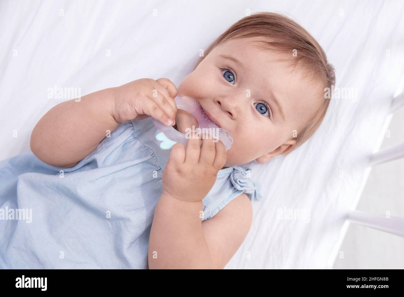 Kleinkind Baby Mädchen beißt Silikon Beißring in ihr Bett. Blick von oben Stockfoto