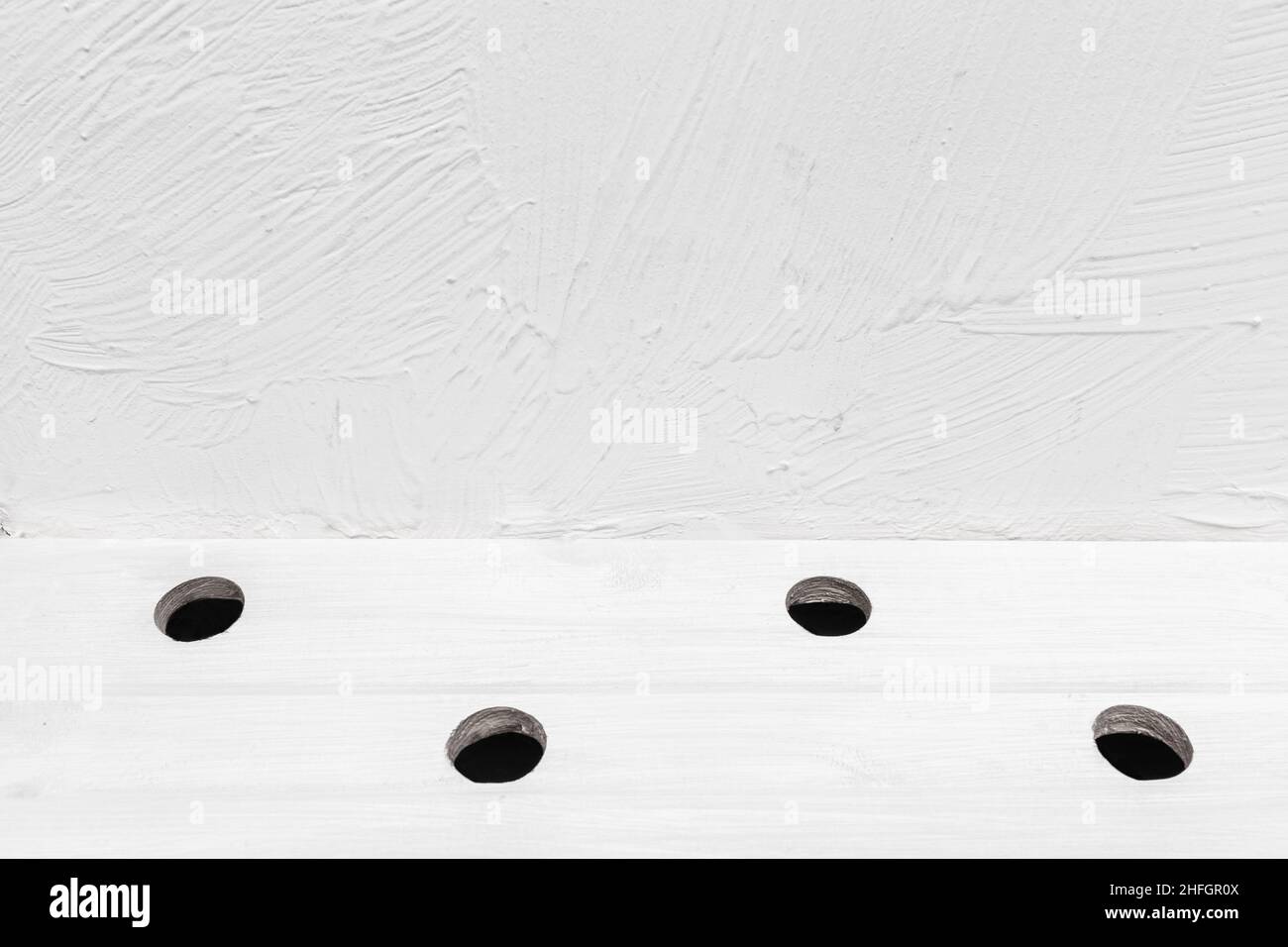 Runde kreisförmige Löcher abstraktes Muster Design in Holz weißen Wand Hintergrundfläche. Stockfoto