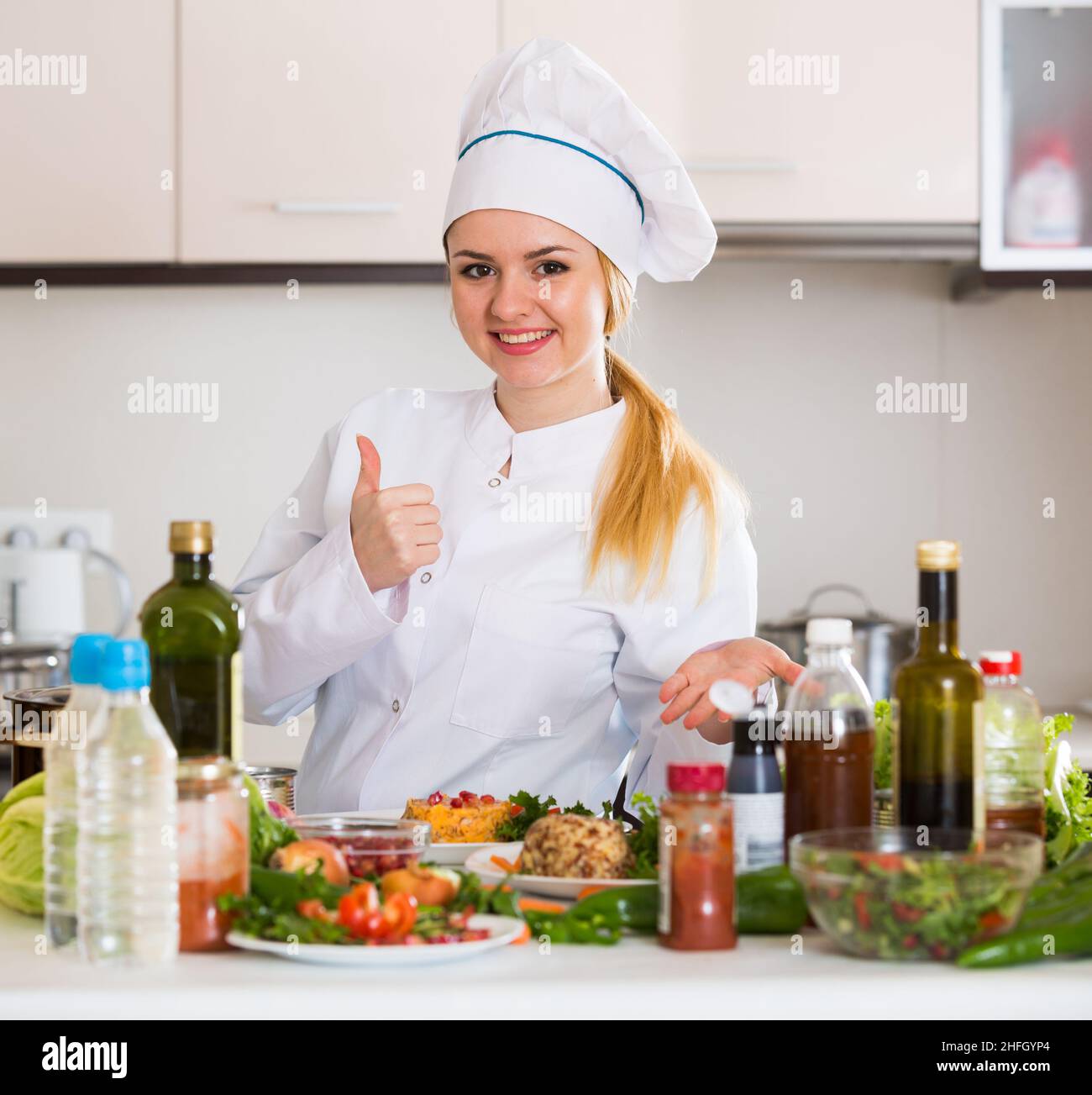 Positiver Koch posiert mit Gemüsemischung und Käse Stockfoto