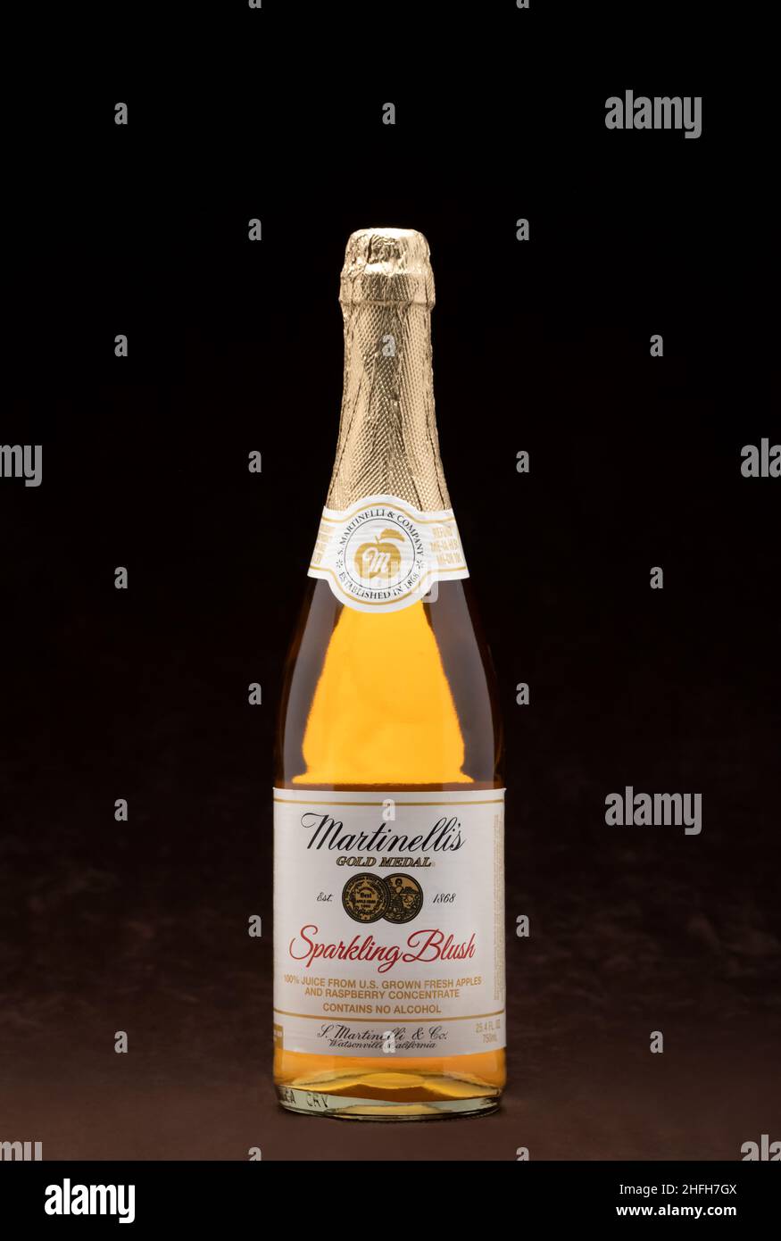 Flasche mit Martinellis funkelndem Apfelwein oder Saft, häufig als alkoholfreier Ersatz für Champagner verwendet, auf braunem Hintergrund mit Kopie sp Stockfoto
