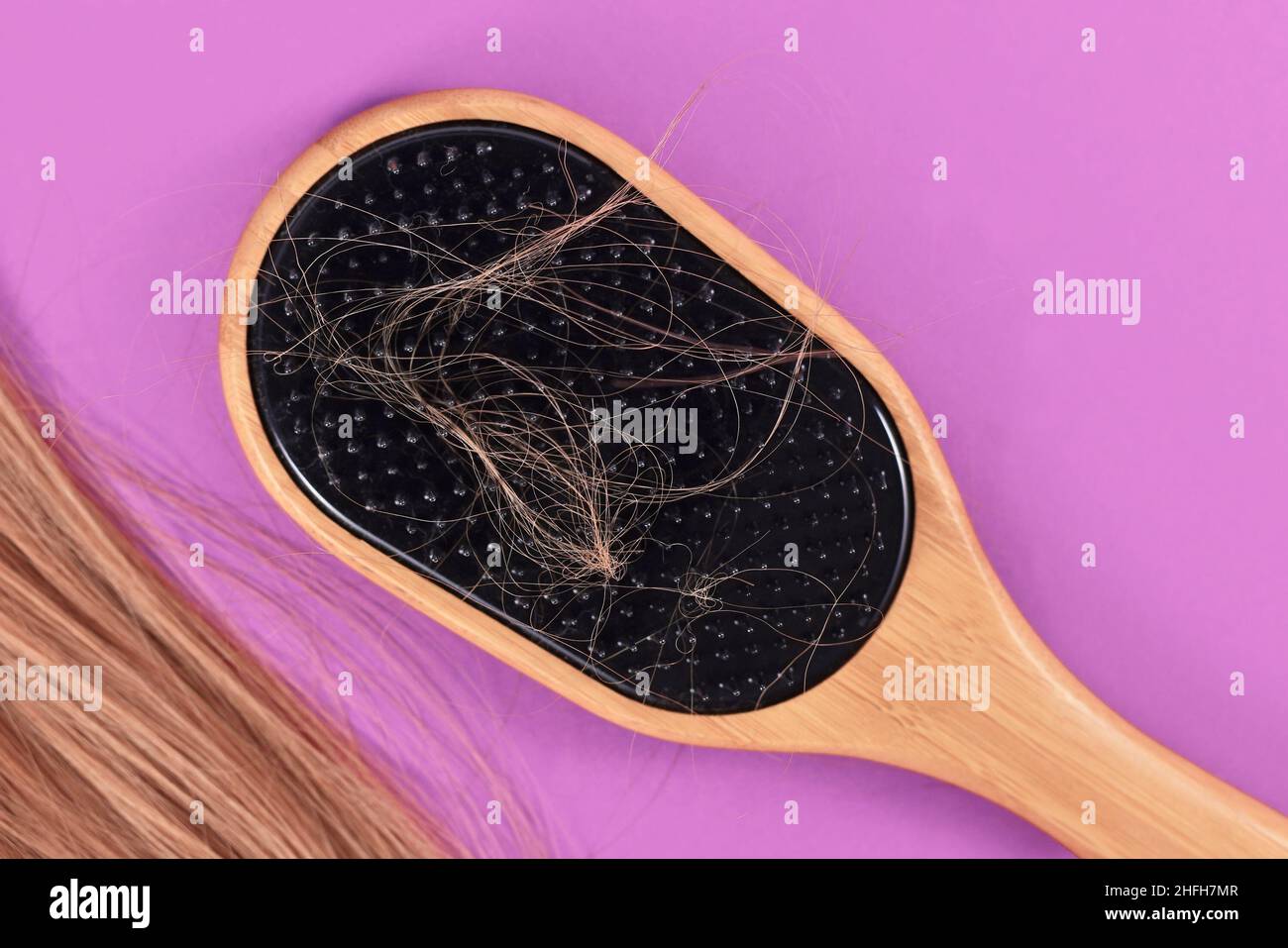 Konzept für das Verlieren von Haaren mit Strängen von blondem Haar in der Haarbürste gefangen Stockfoto